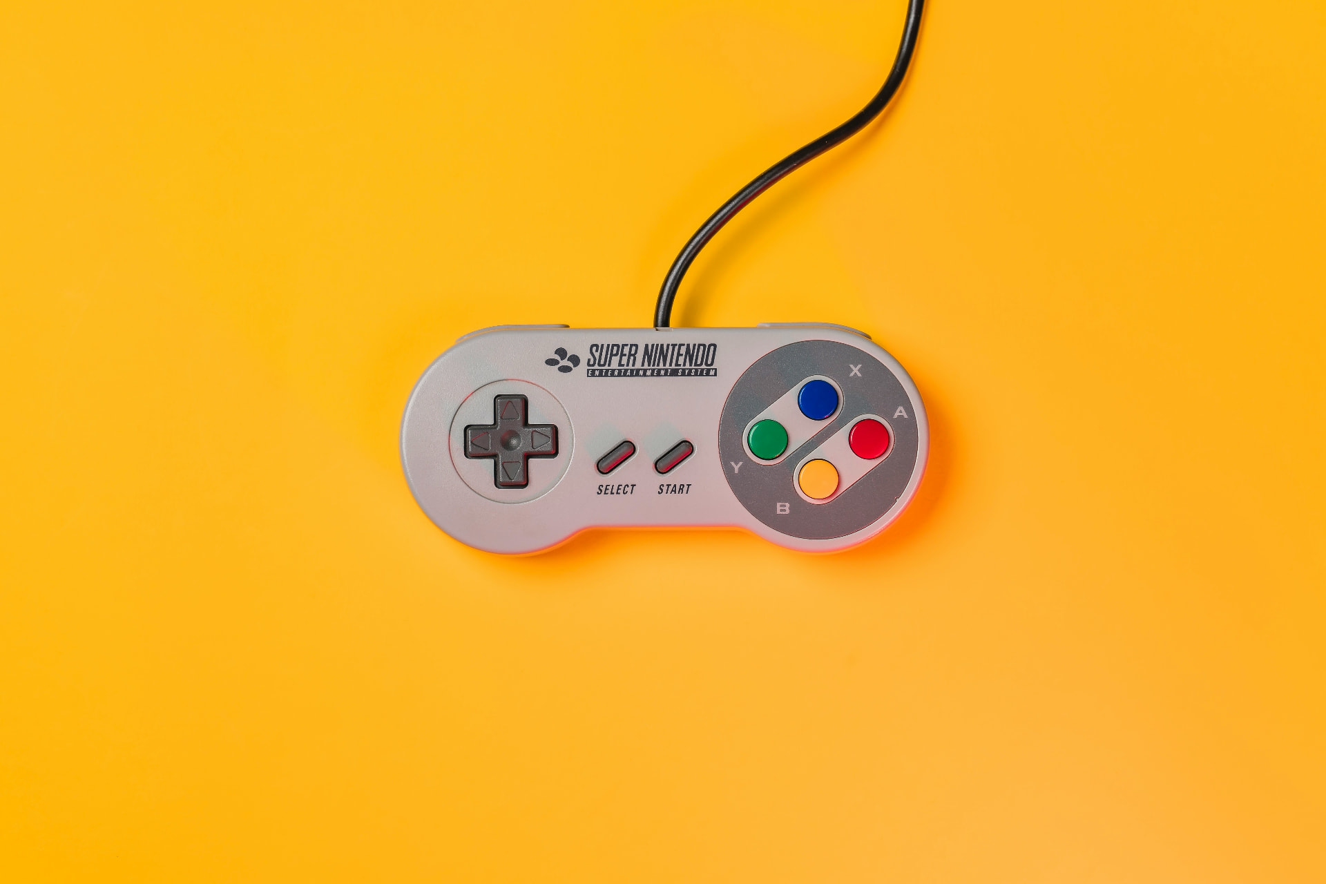 Super Nintendo controller photographed flat on a bright yellow background